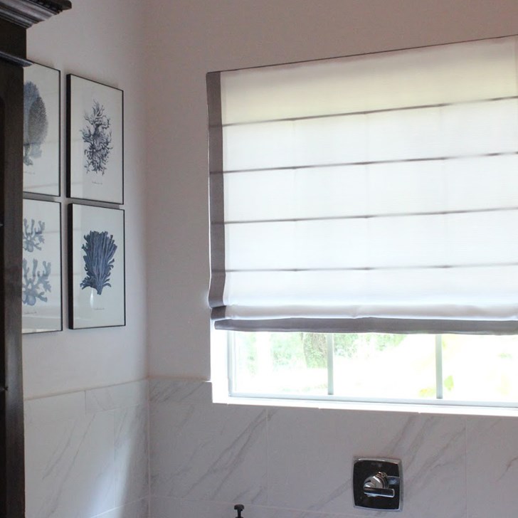 Light filtering roman shade with seams and edge banding.